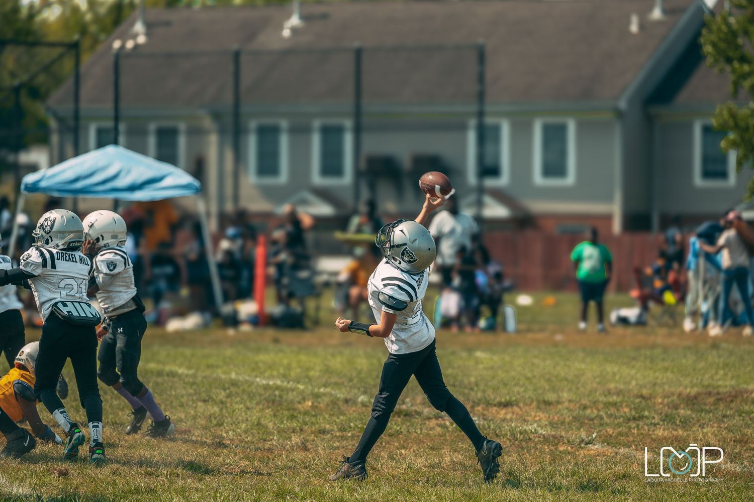 Young football player throwing the ball during a game on a sunny field.