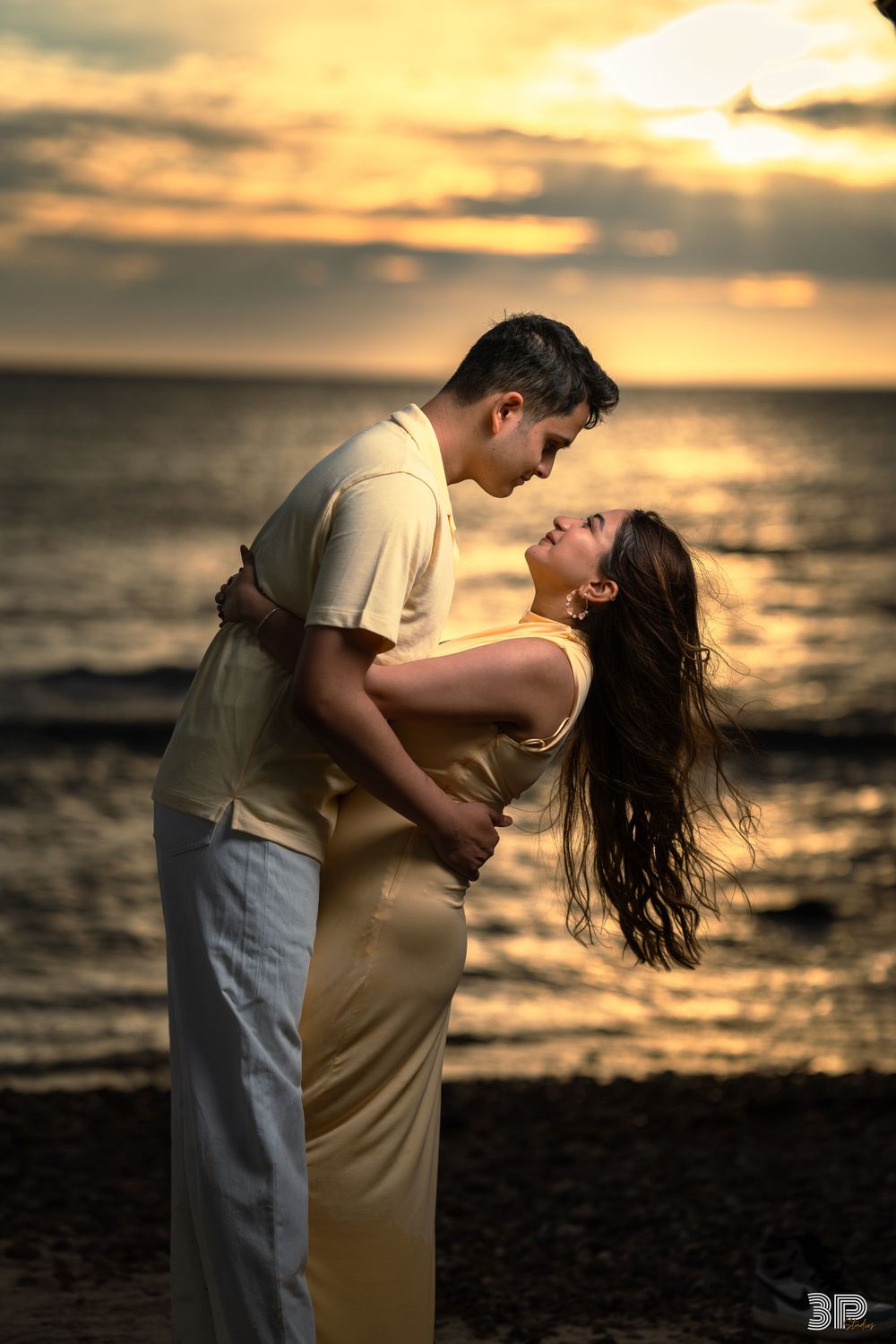 Couple holding hands and walking together at sunset during a pre-wedding photoshoot, surrounded by warm golden light.