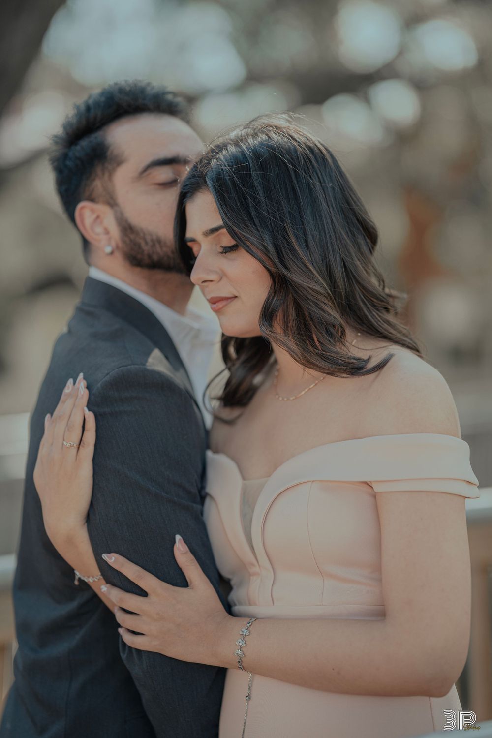 Romantic engagement photo of couple in formal wear sharing an intimate moment.