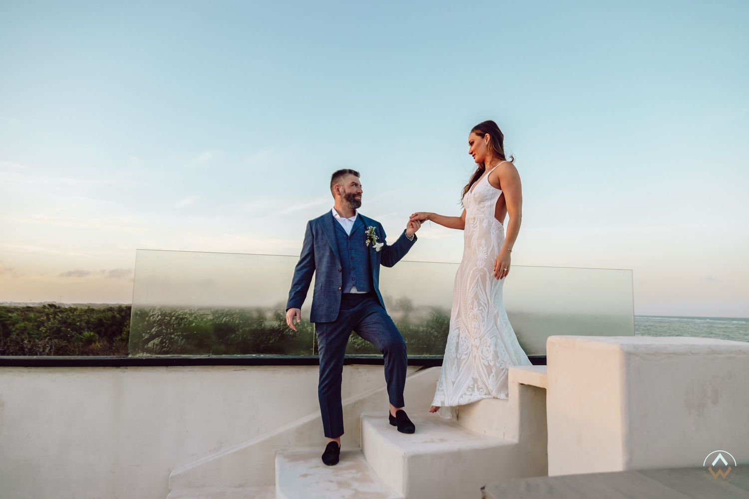 A couple shares a romantic moment on a rooftop terrace overlooking the ocean at sunset, Papaya Playa Tulum Wedding.