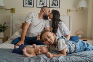 A family relaxes together on a cozy bed, sharing intimate moments and cuddles in a warmly lit bedroom.