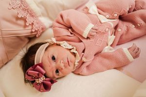 A collection of pink-toned photographs showing a baby wearing a pink knit sweater and bow headband.