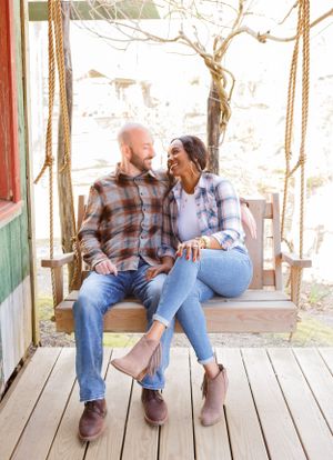 Couple sitting on rustic wooden porch swing sharing intimate moments together.