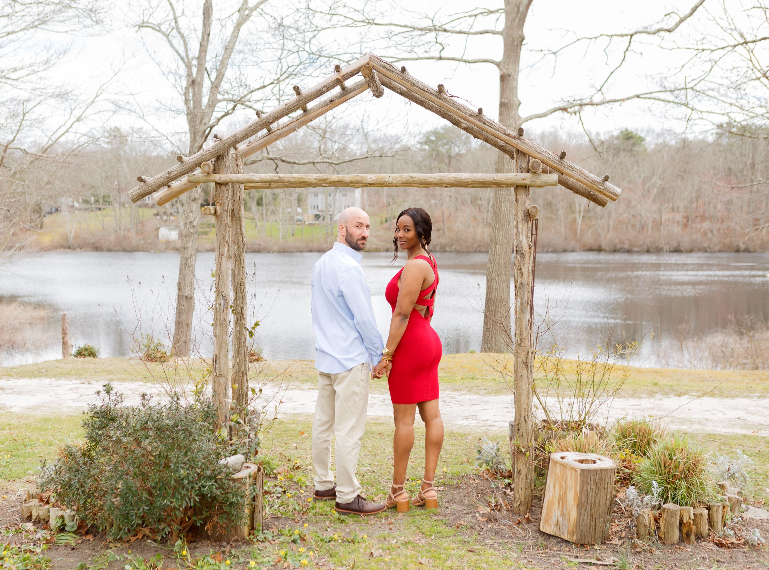 Scenic outdoor engagement photos with lake and bare trees in background.