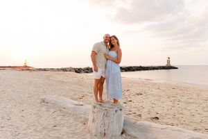 Romantic beach engagement photos at sunset with lighthouse in background by Hamptons photographer.
