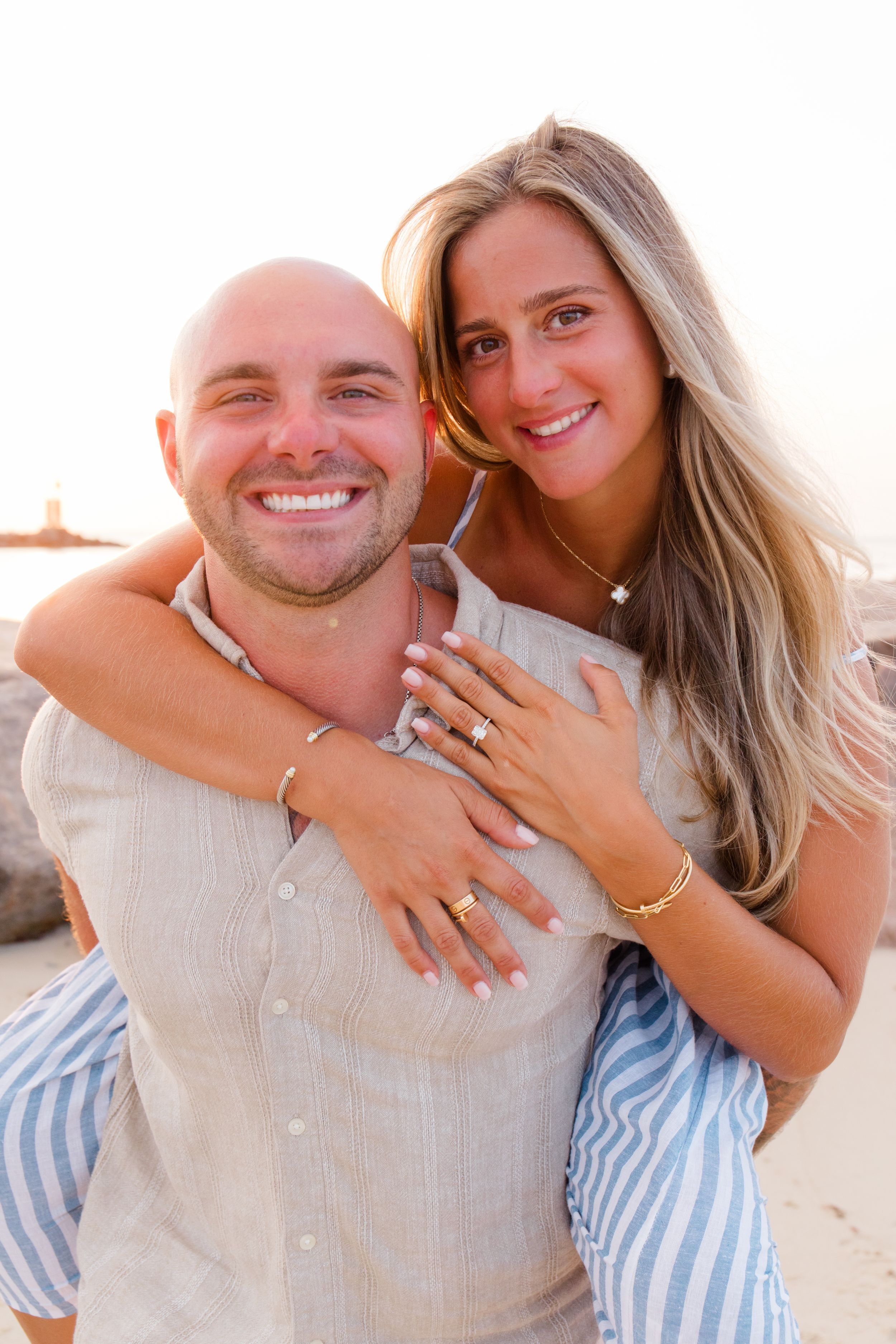 A couple in light summer clothing sharing joyful moments on the beach during a photoshoot by Hamptons photographer.