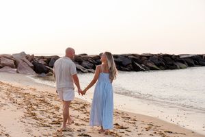 A couple walking hand in hand along the shoreline during sunset by Hamptons photographer.