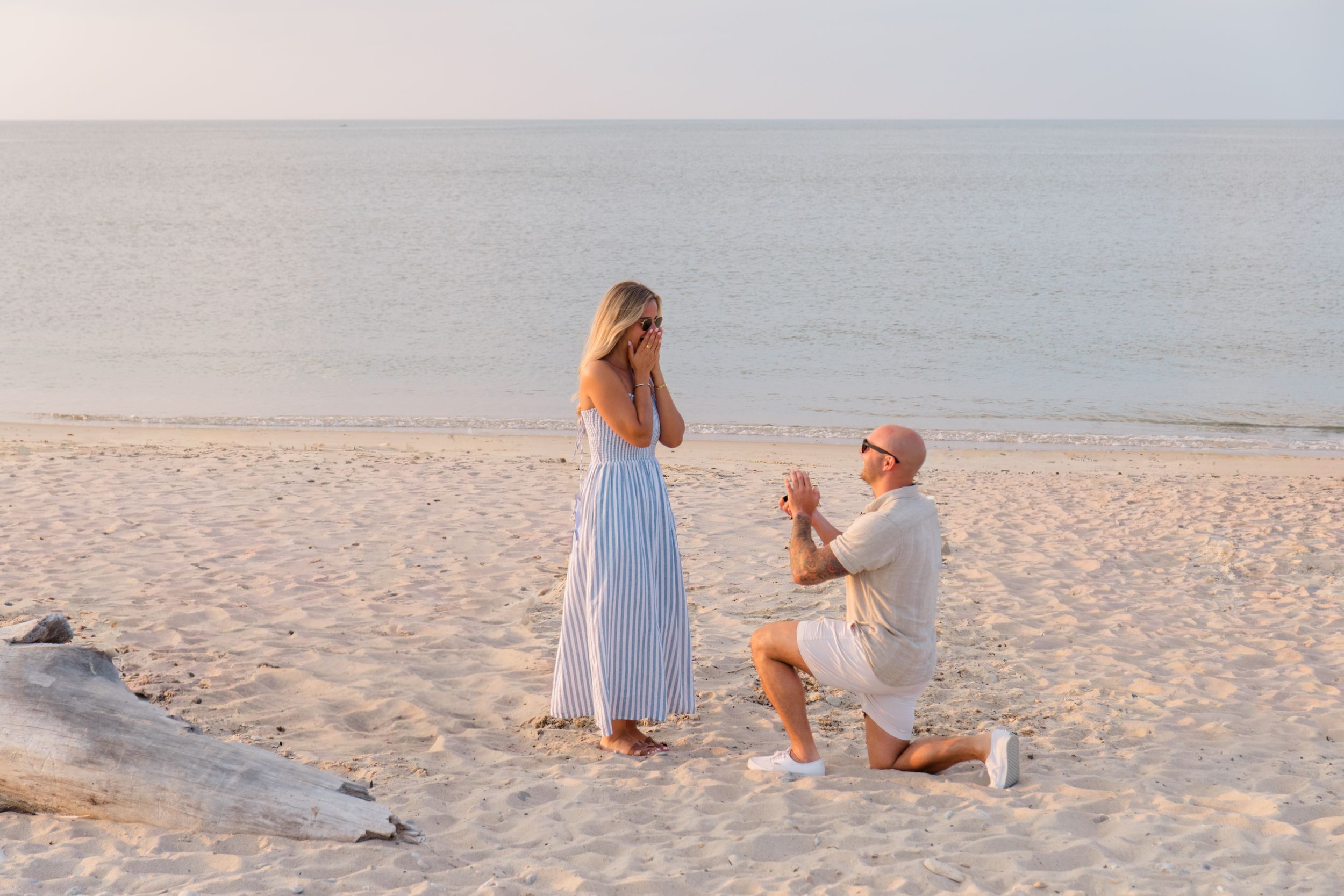 A surprise proposal moment captured on a sandy beach at golden hour by Hamptons photographer.