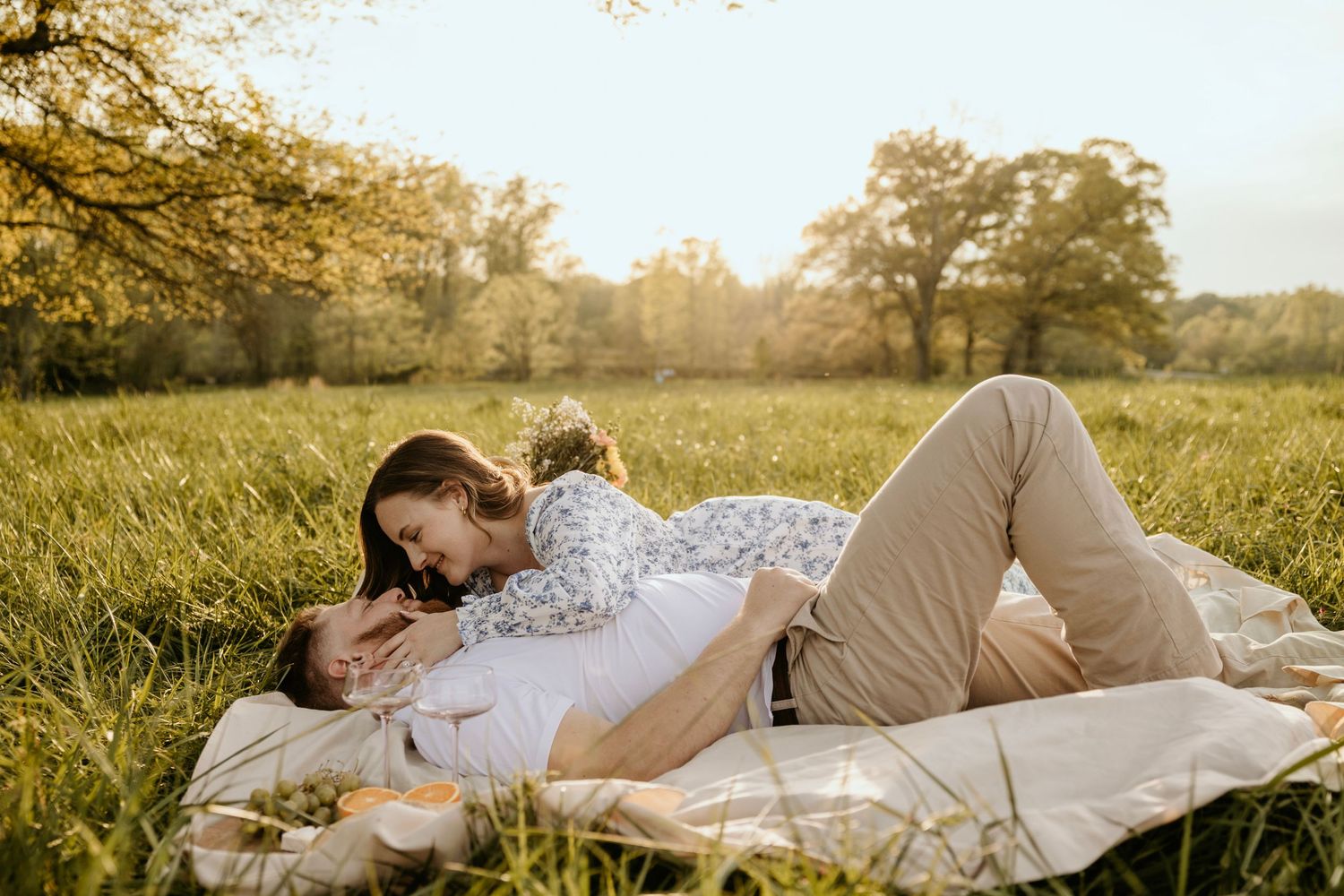 Intimate couple moment on picnic blanket in sunny meadow.