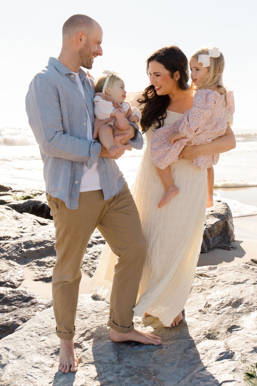 Family enjoying playful moments together on a sunny beach.