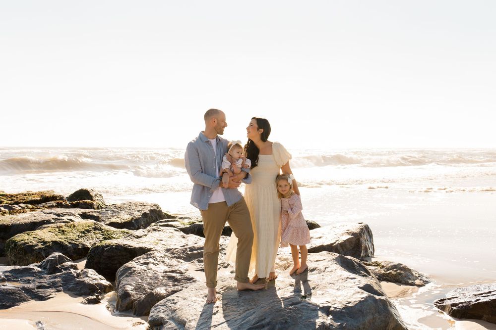 Candid family photoshoot on a rocky beach during golden hour.