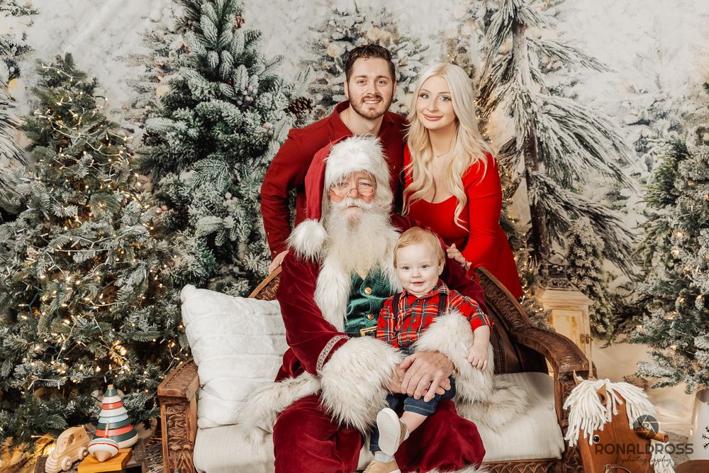A festive holiday photo session with Santa Claus in a snowy winter wonderland setting with decorated Christmas trees. Santa Photos Galveston