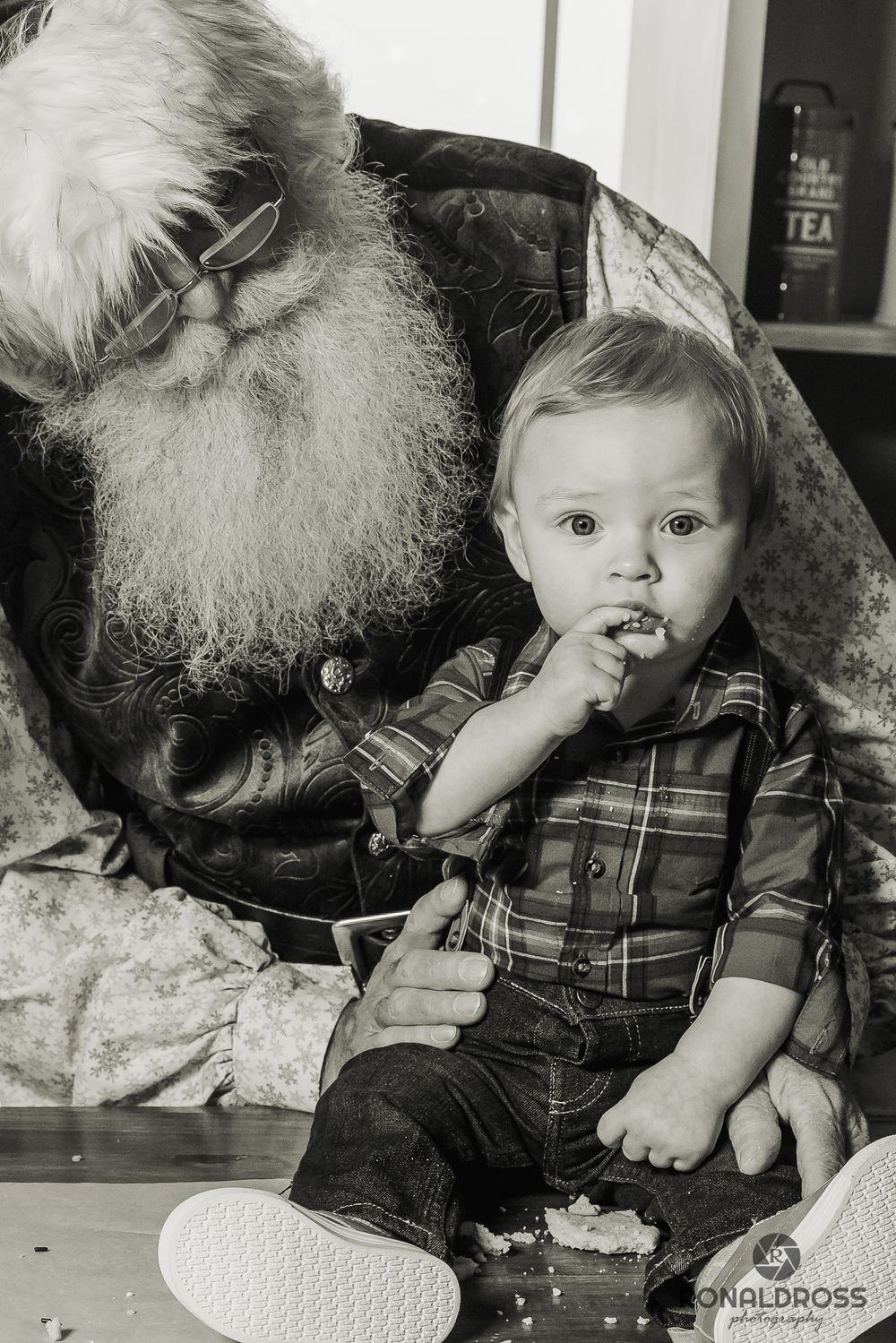 A small child in plaid clothing sits with Santa Claus in a series of black and white photos showing various expressions. Santa Photo Webster