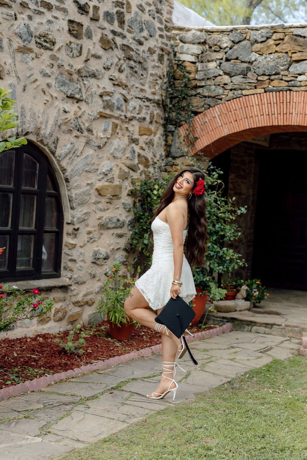A series of photos showing someone in a white dress posing against a rustic stone wall with brick archways and greenery.