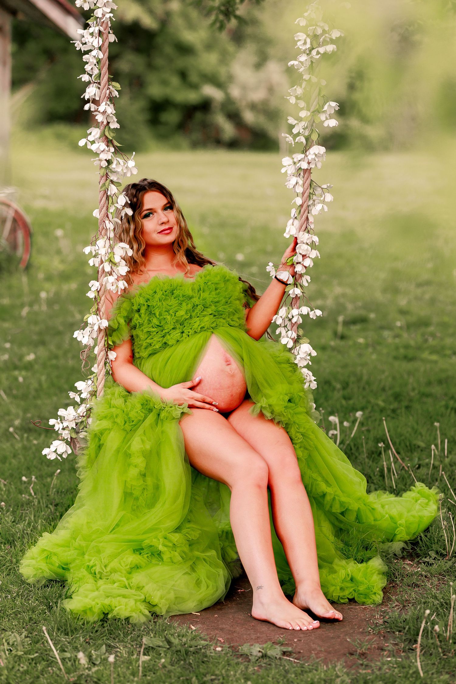 Spring maternity photos with white flowering branches and a flowing lime green dress.