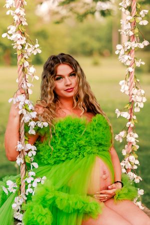 A vibrant lime green tulle dress photographed against flowering branches in a spring garden setting.