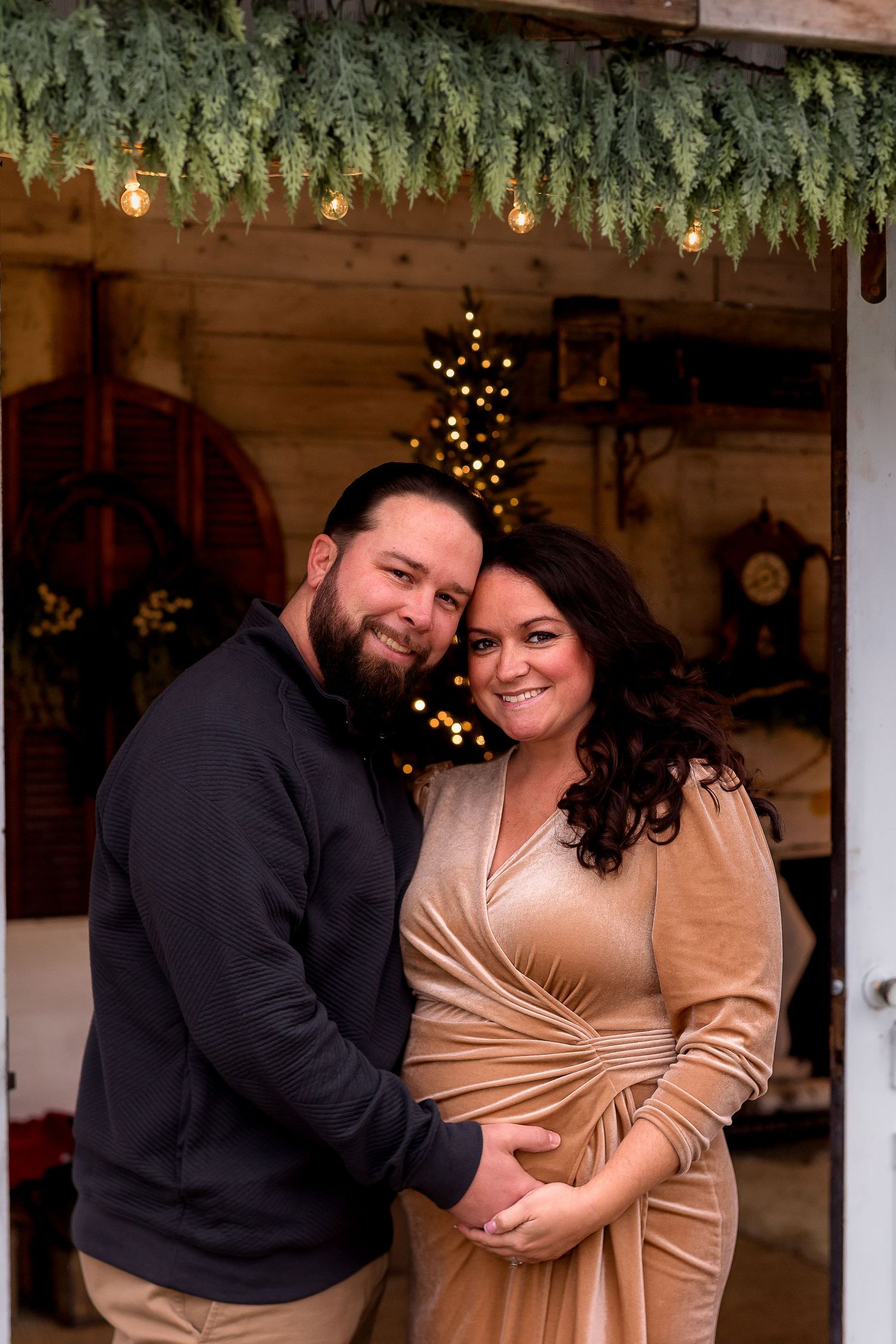 Indoor winter photoshoot with evergreen decorations and twinkling lights creating a festive atmosphere.