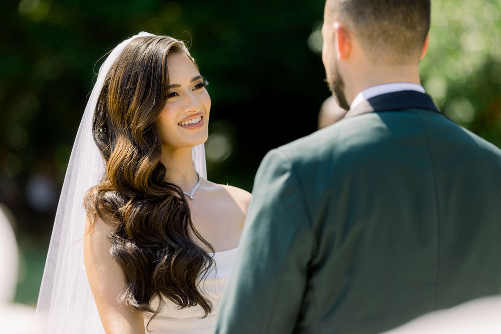 Wedding couple exchanging vows during outdoor ceremony surrounded by greenery.