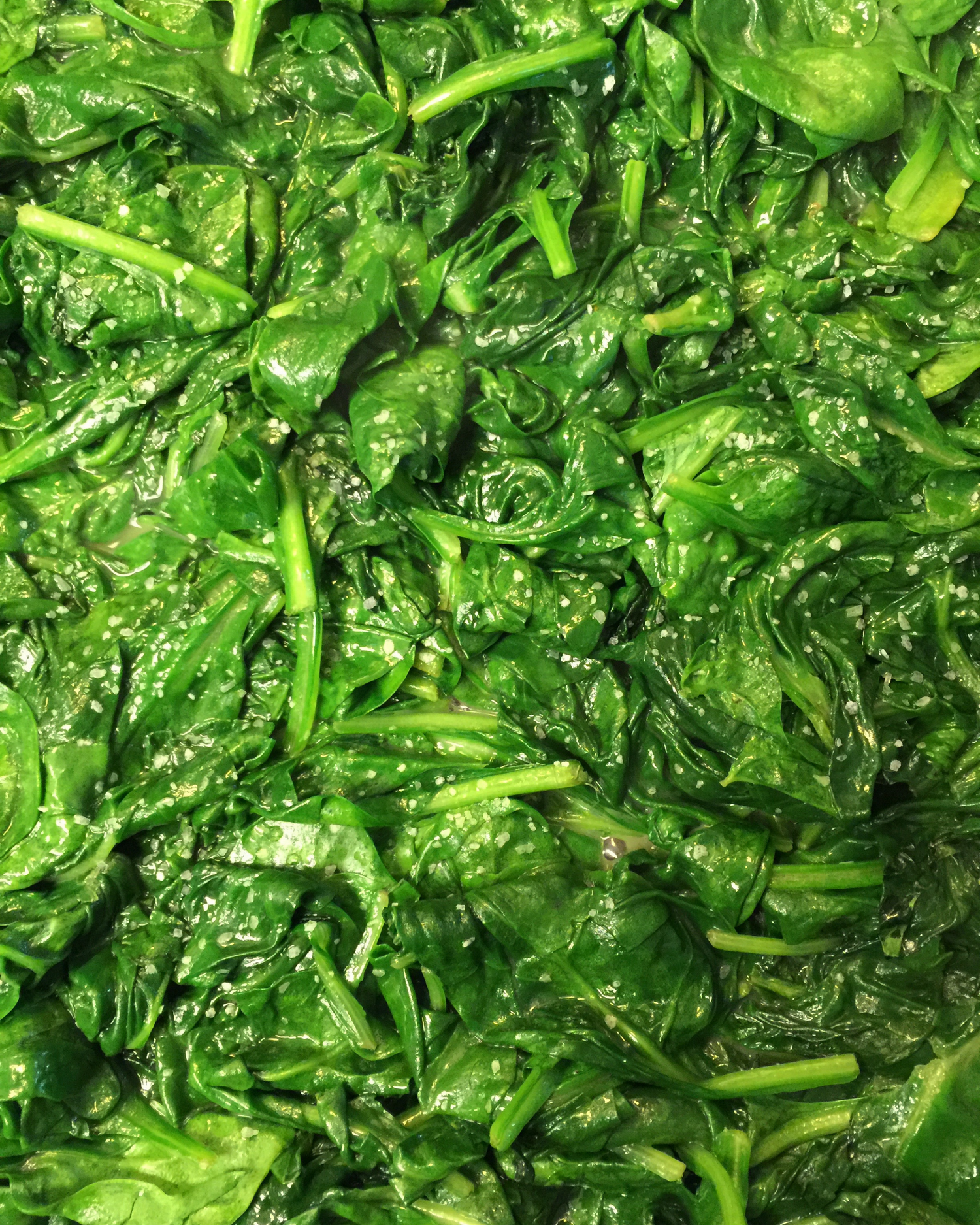 Fresh chopped spinach leaves glistening with moisture in a close-up view.