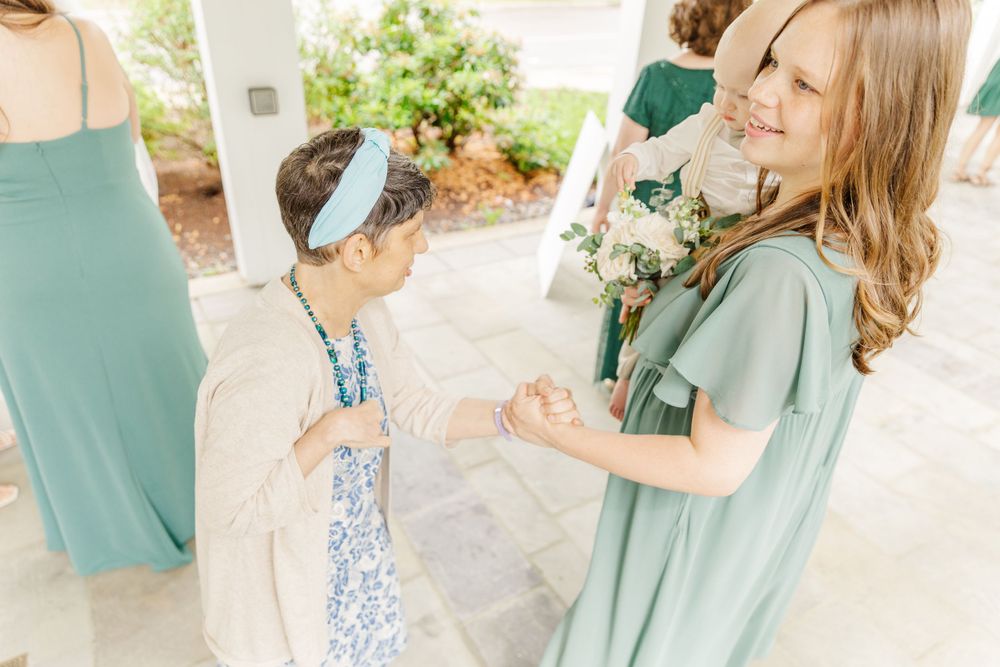 Two people in mint green gowns share a joyful moment at an outdoor wedding venue.