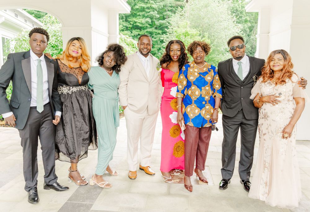 Wedding attendees in colorful formal attire pose together under white archway.