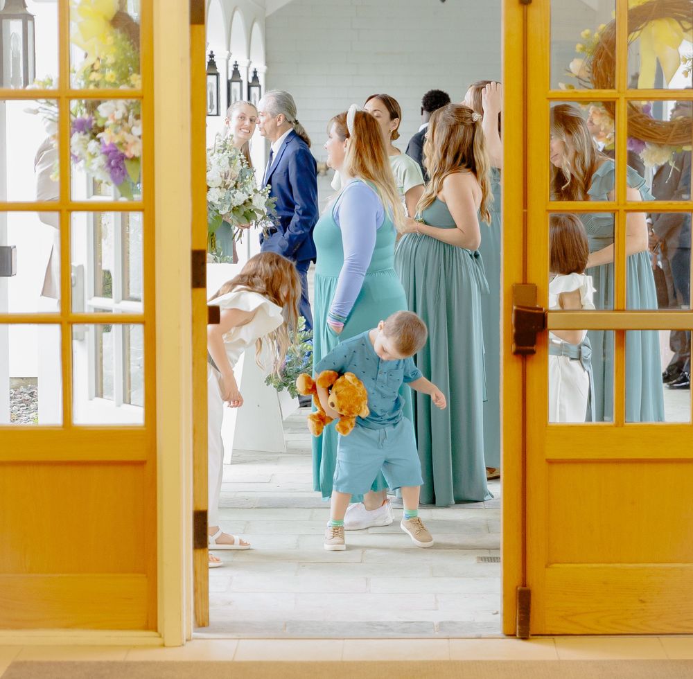 Wedding party in mint green dresses gathered in doorway with yellow trim.