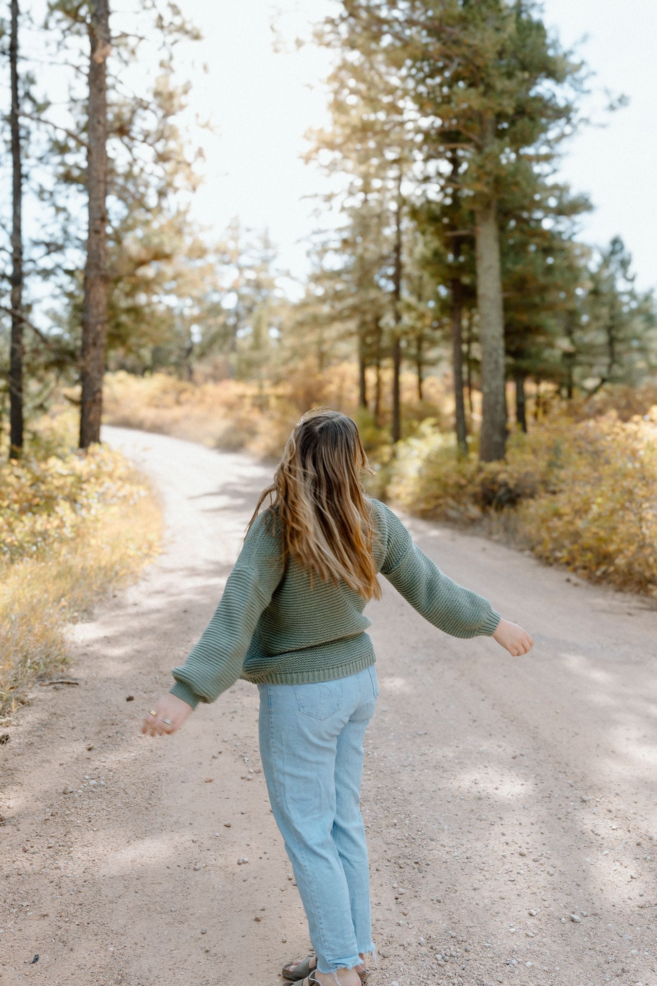 A person in a white sweater standing in a snowy forest landscape. Colorado Springs Photographer