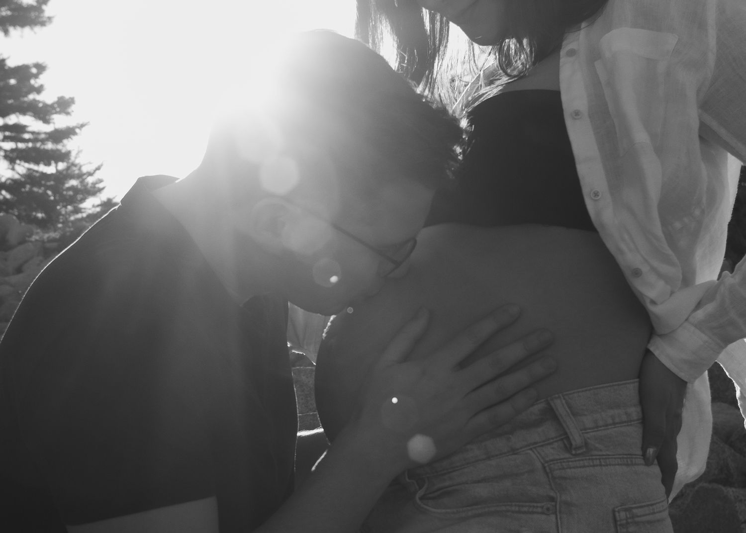 An intimate black and white maternity photo with a couple sharing a tender moment.
