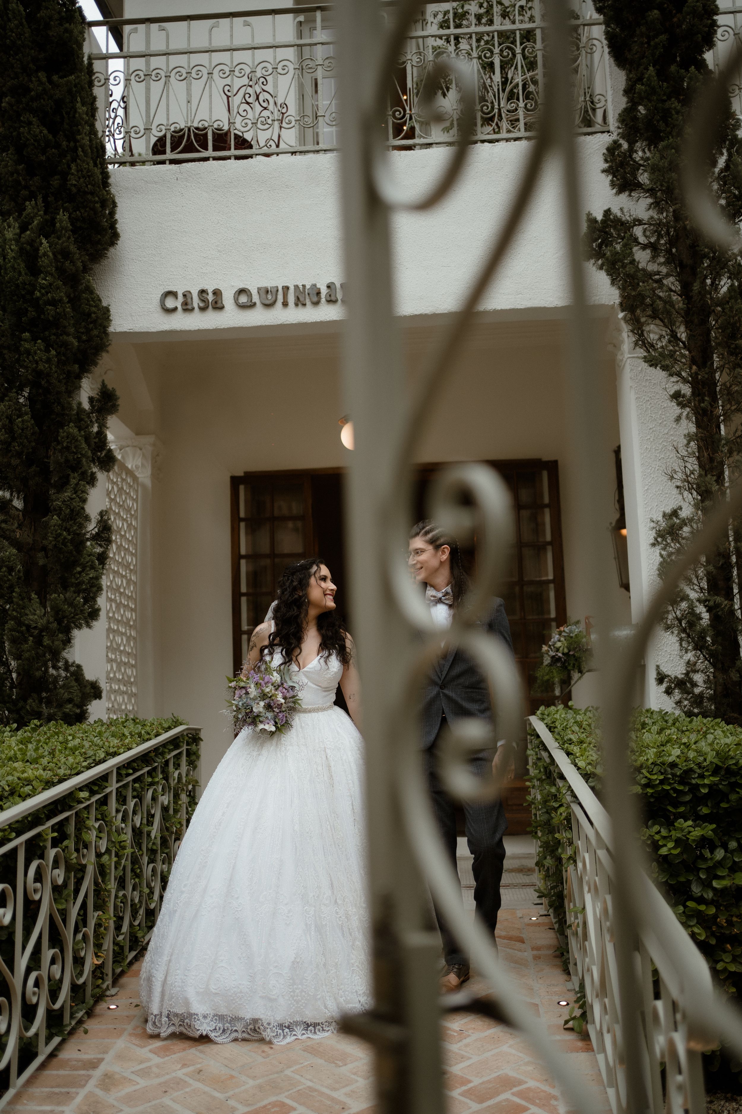 Romantic wedding portrait at Casa Quinio with ornate balcony and cypress trees.