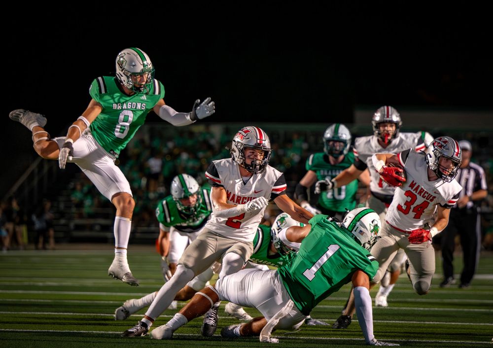 Dynamic action shot of football players in red and green uniforms during a game.