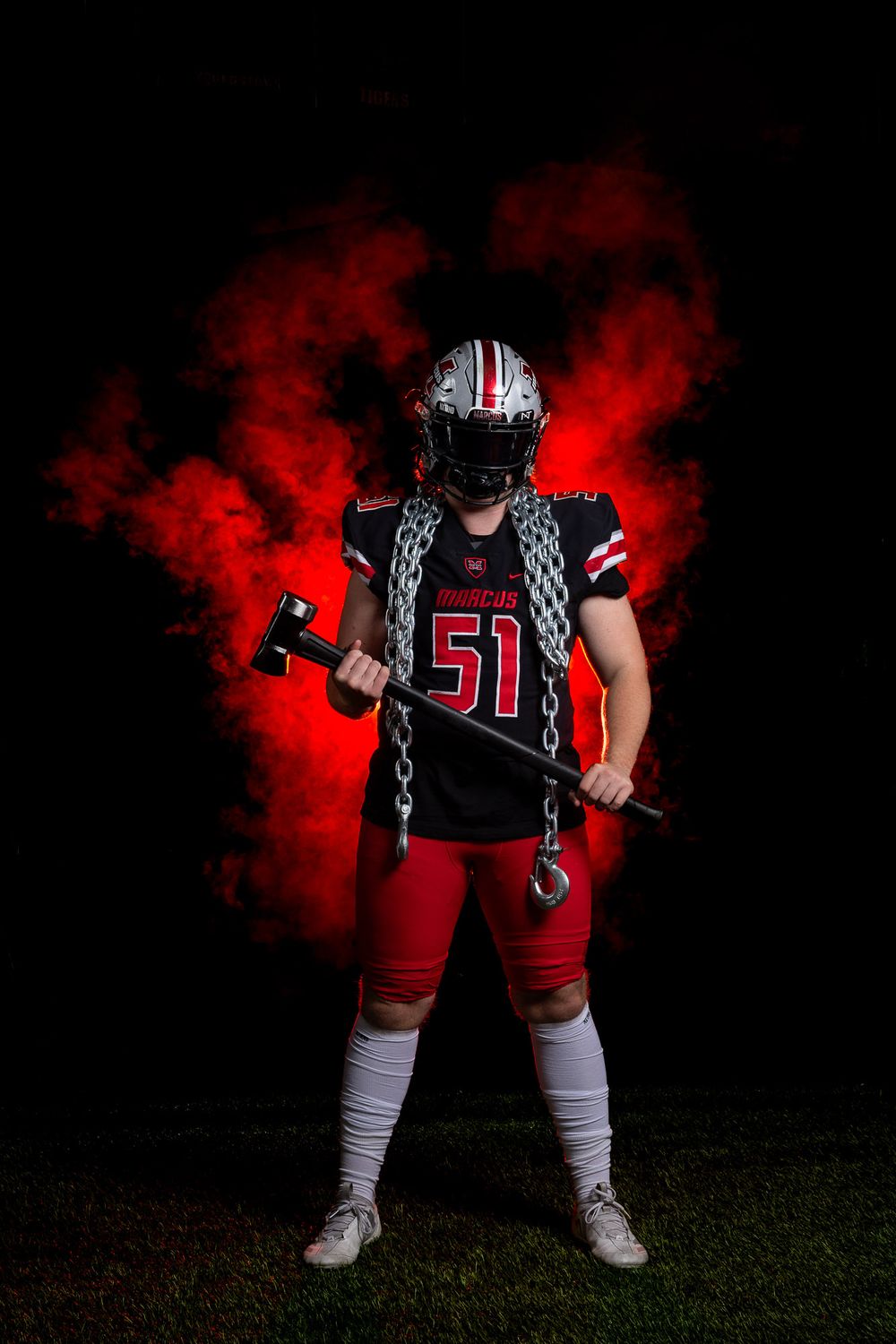Football player in uniform number 51 poses with chain against red smoke effect.