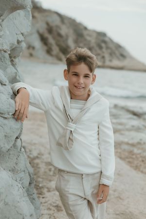 niño de comunión posando junto al mar