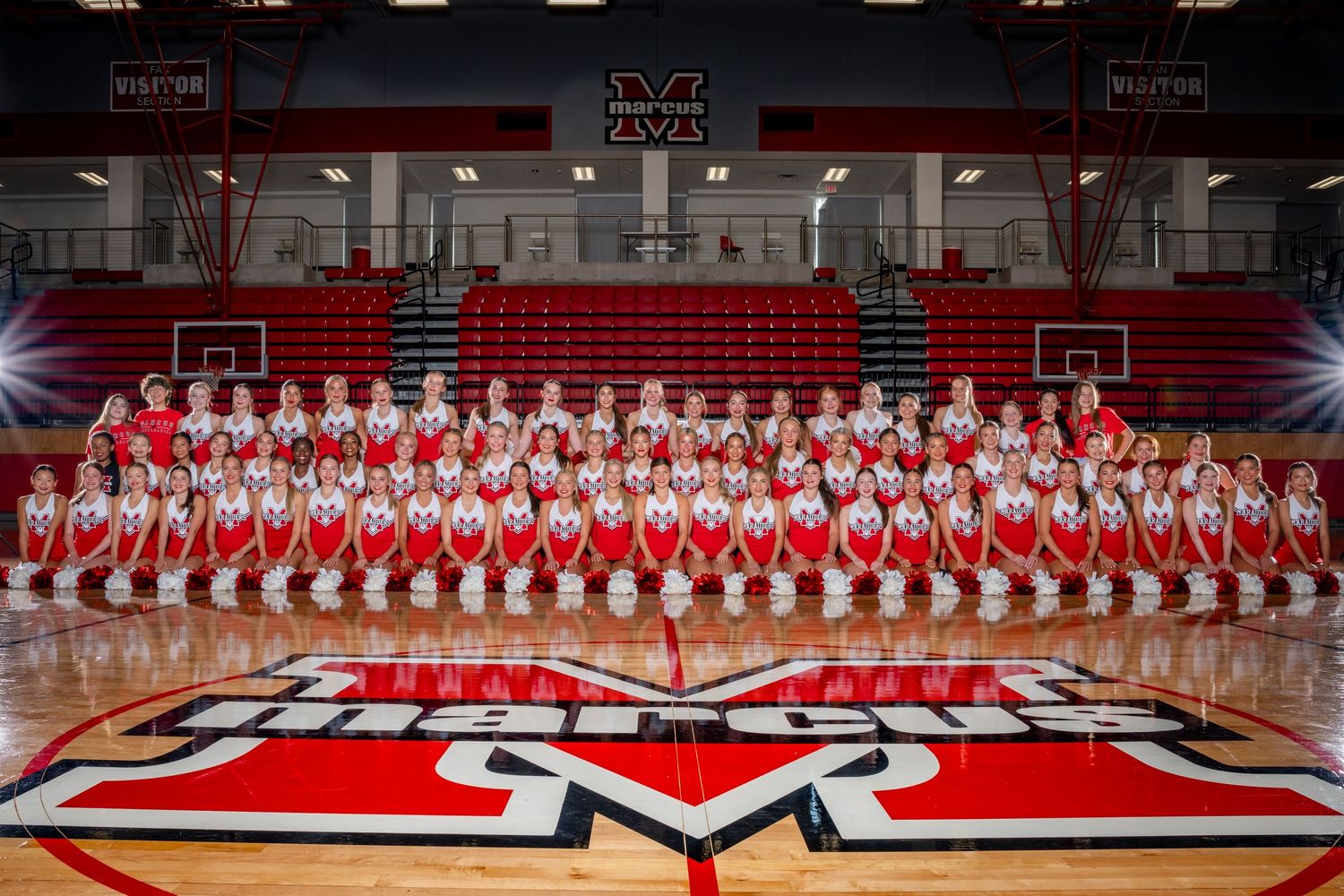 Large group photo of Marcus sports teams in red and white uniforms on basketball court.