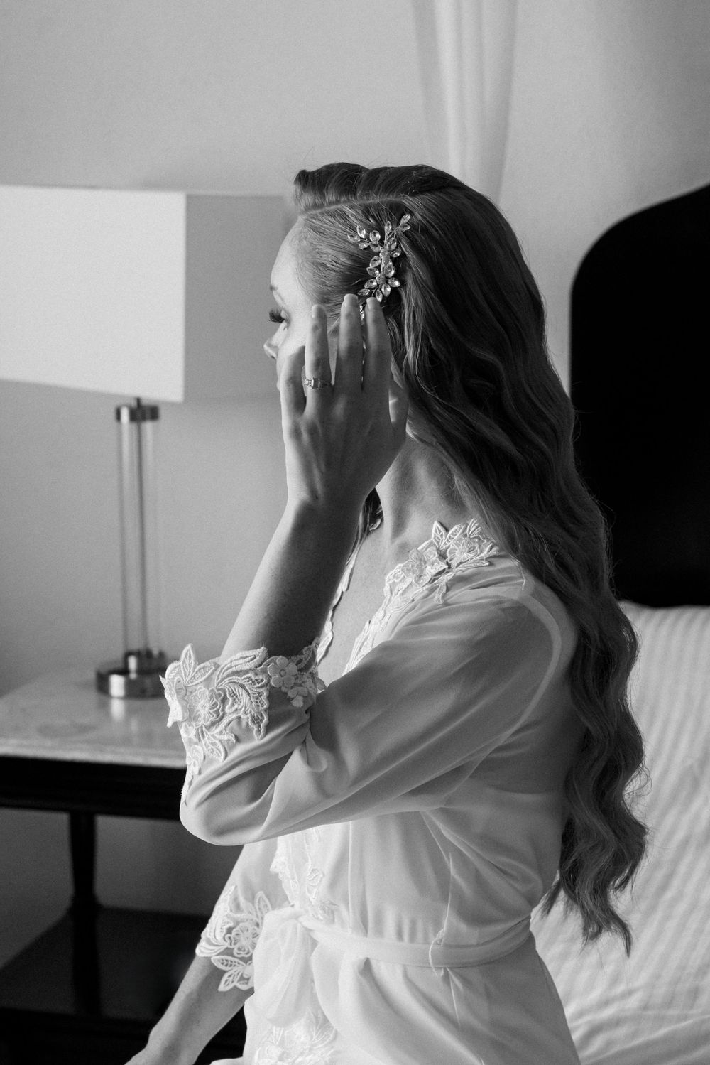 Black and white portrait of woman in lace robe getting ready on wedding morning.
