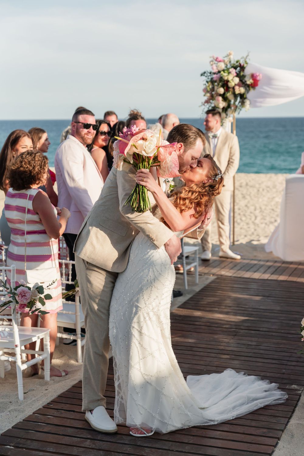Newlyweds share their first kiss during a beachside wedding ceremony.