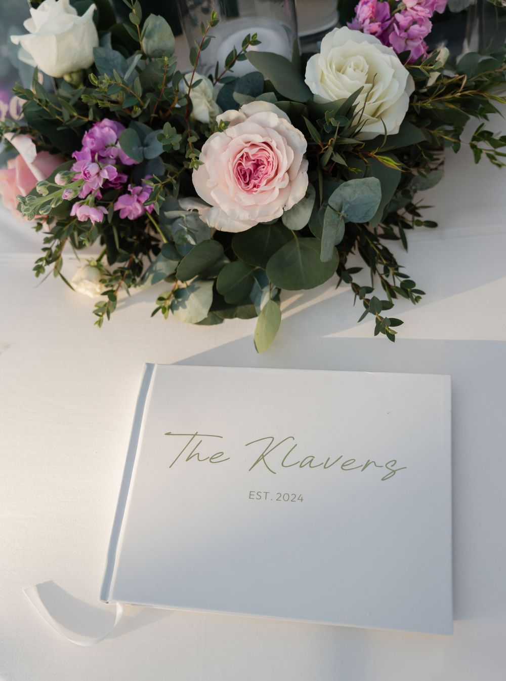 Wedding guestbook labeled 'The Klavenes' with pink and white floral arrangement.