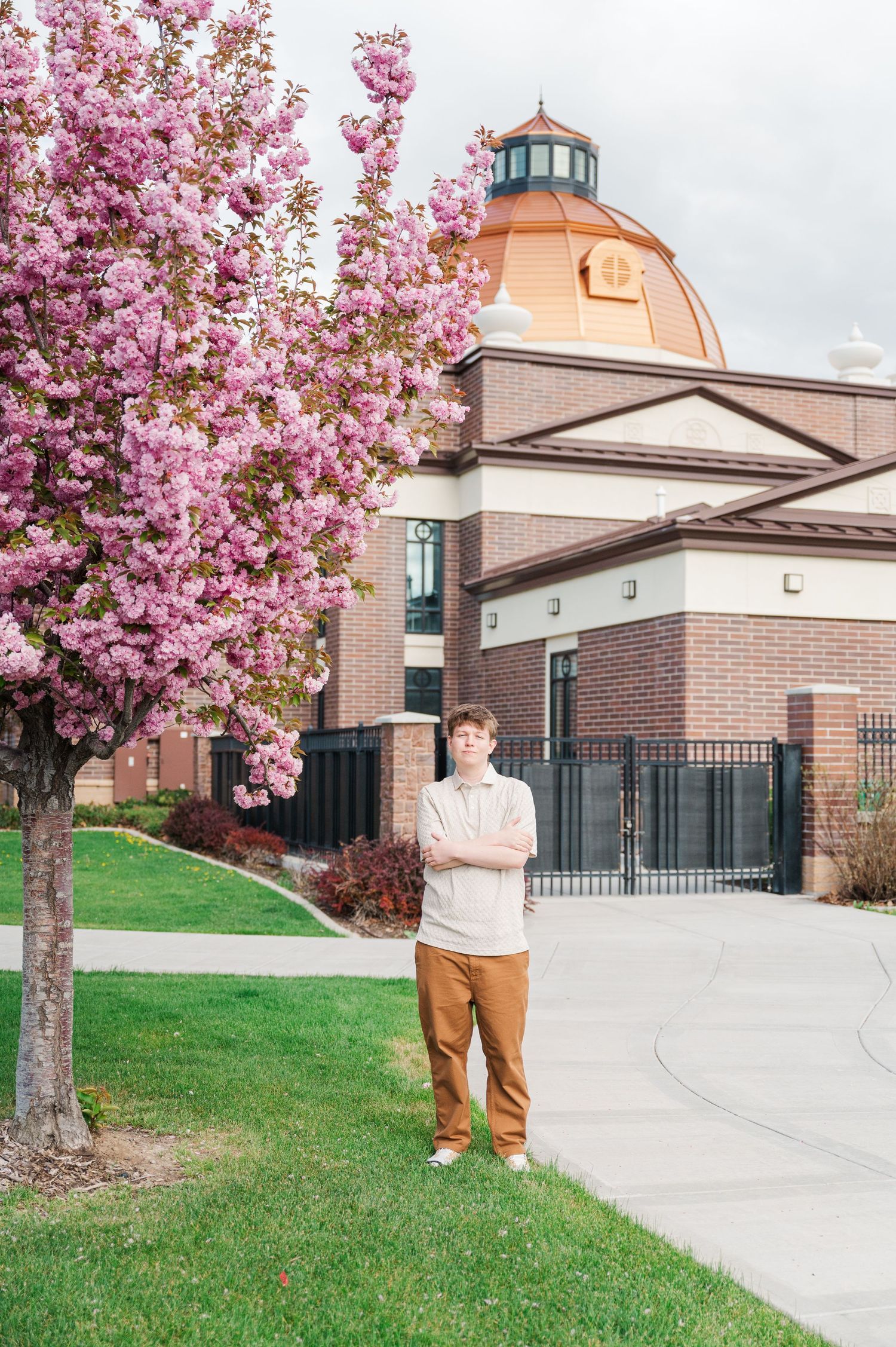 Cherry blossoms frame a brick building with a dome and architectural details.