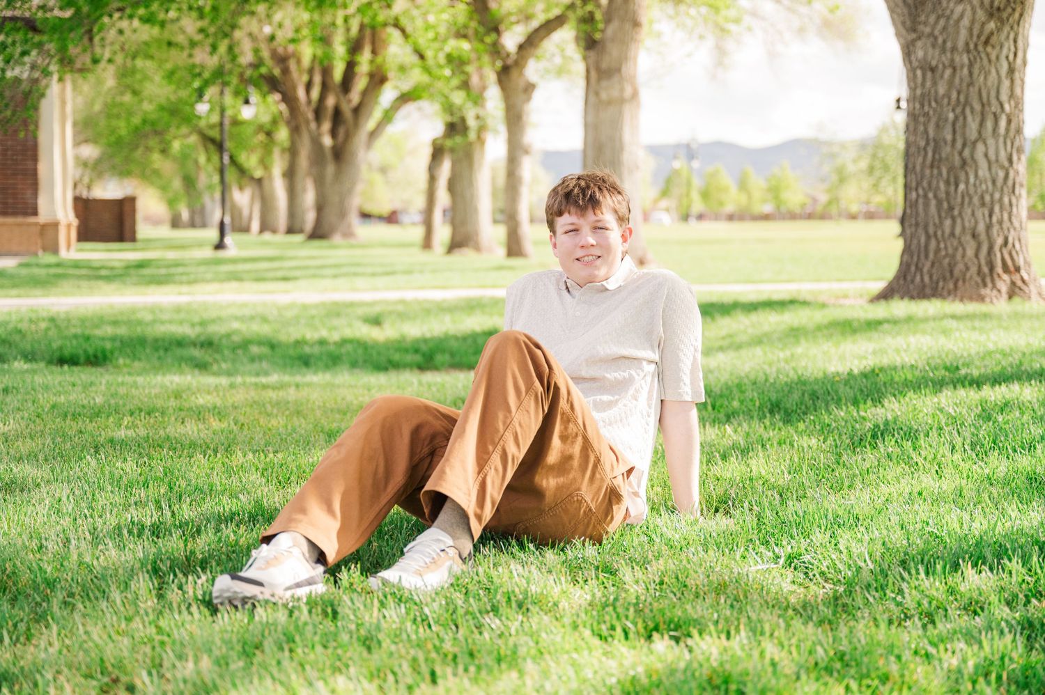 Relaxed outdoor portrait on green grass with trees in background.