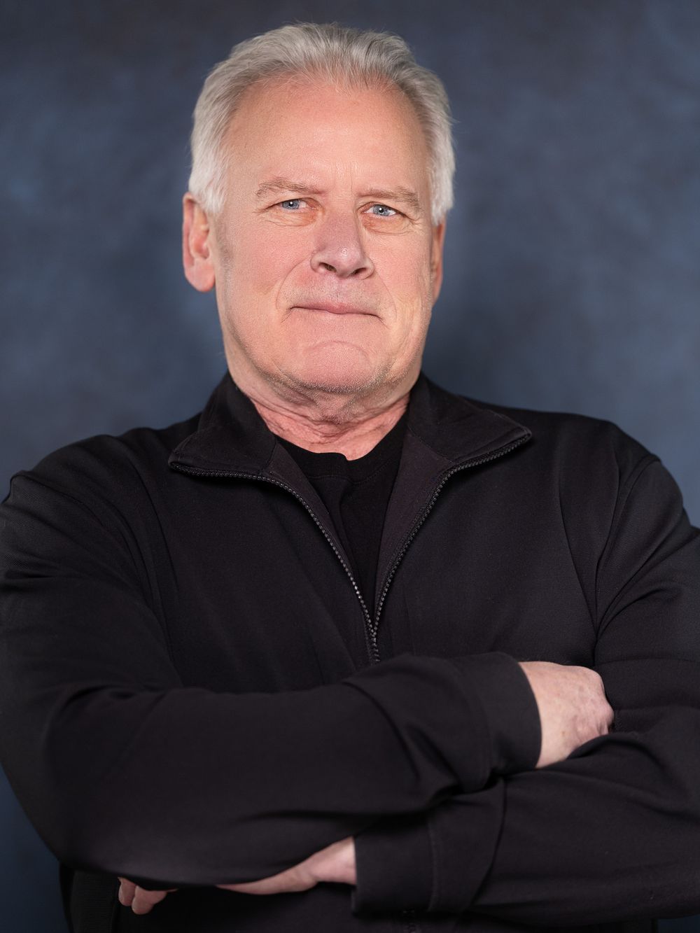Professional headshot series showing different poses of a person in black attire against a dark blue background.