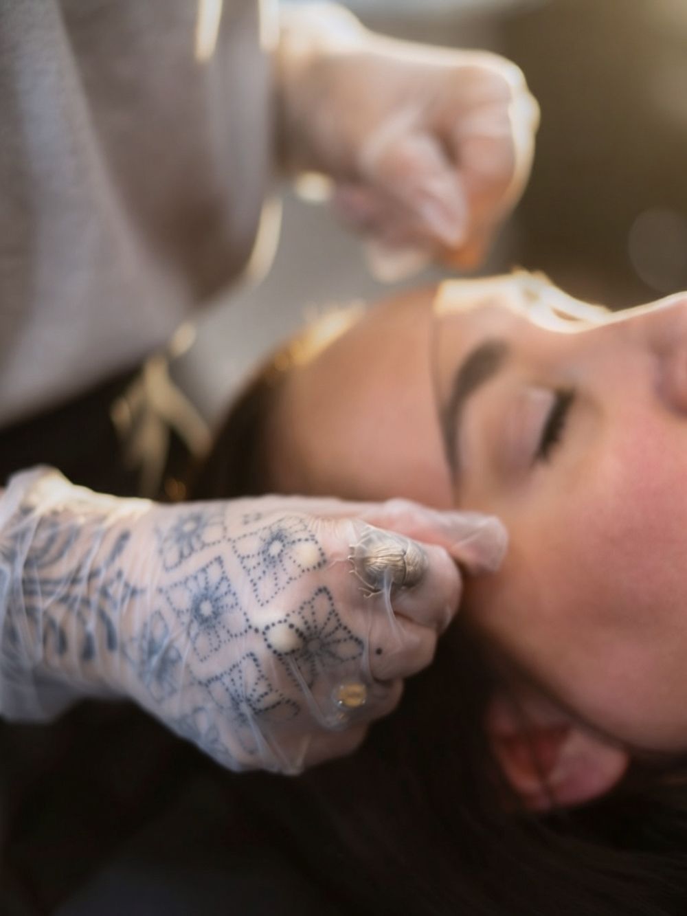 Closeup of a tattoo artist's gloved hands working on a client during a tattoo session.