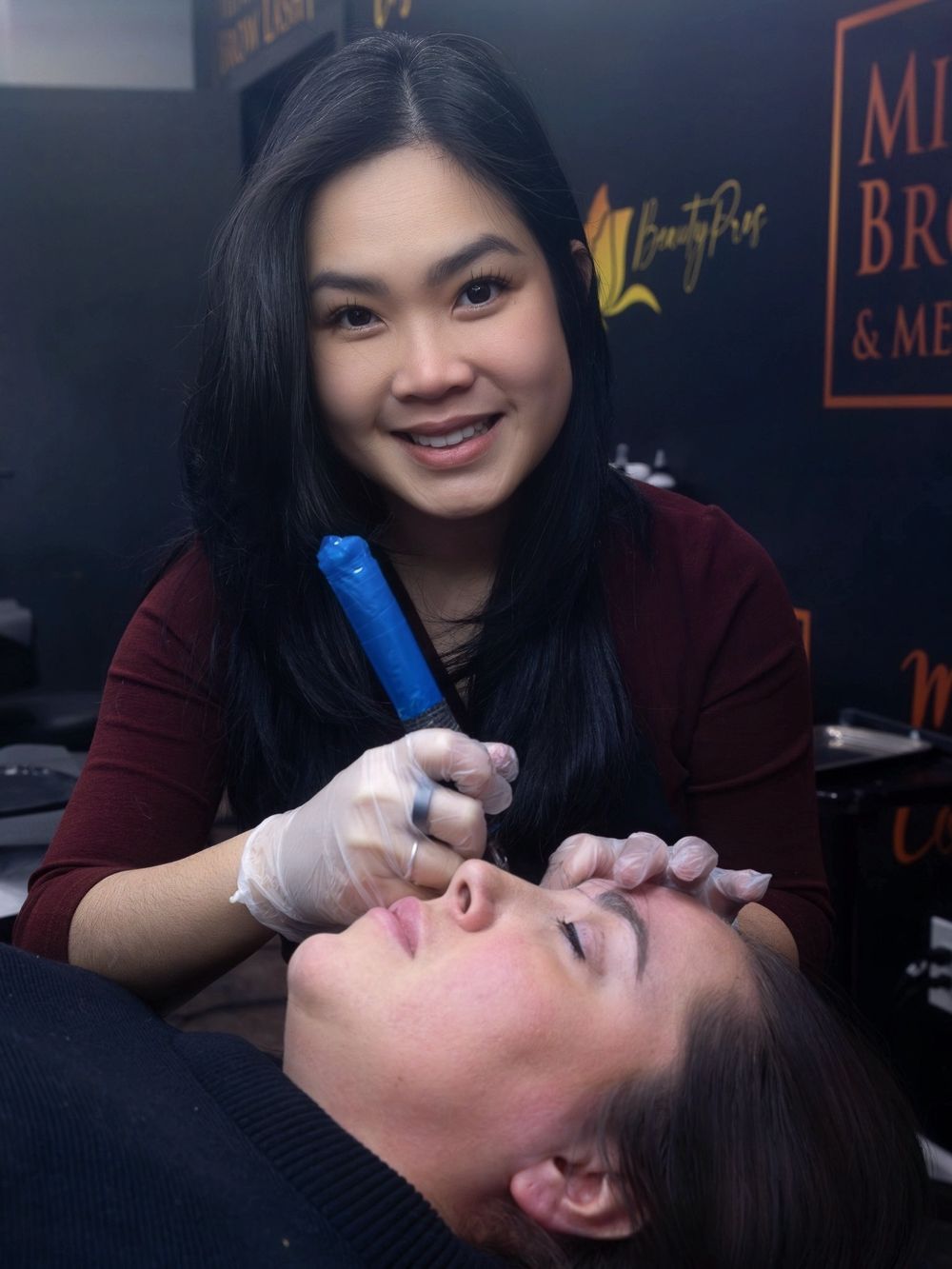 A beauty technician performs an eyelash extension treatment on a client in a salon setting.