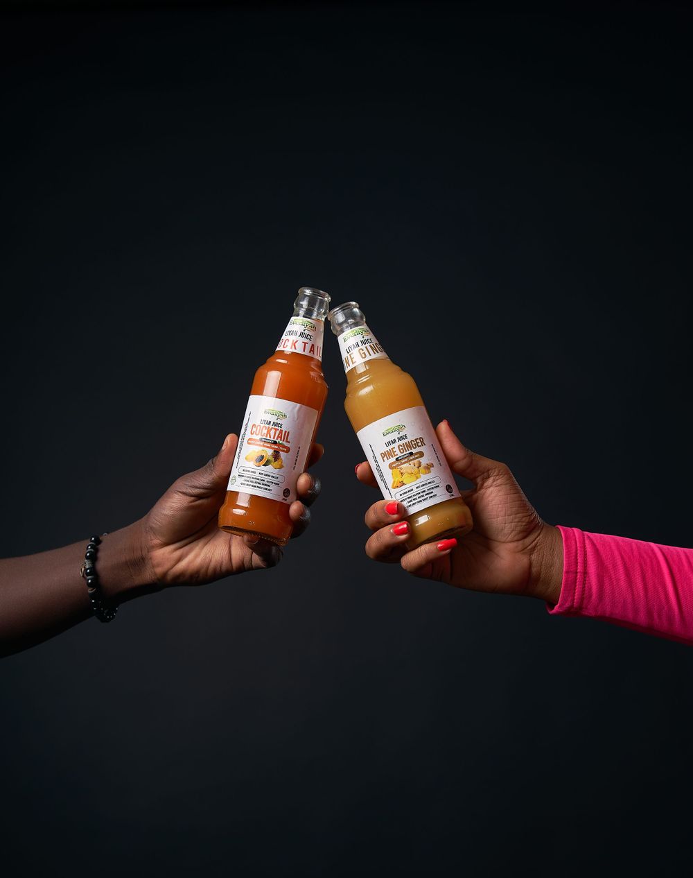 Hands reaching across dark background holding orange juice bottles in dramatic lighting.