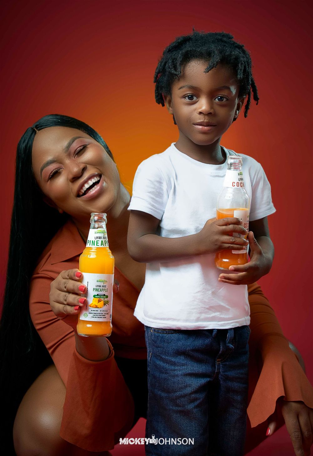 Lifestyle product photography showing enjoyment of orange juice drinks against warm red background.