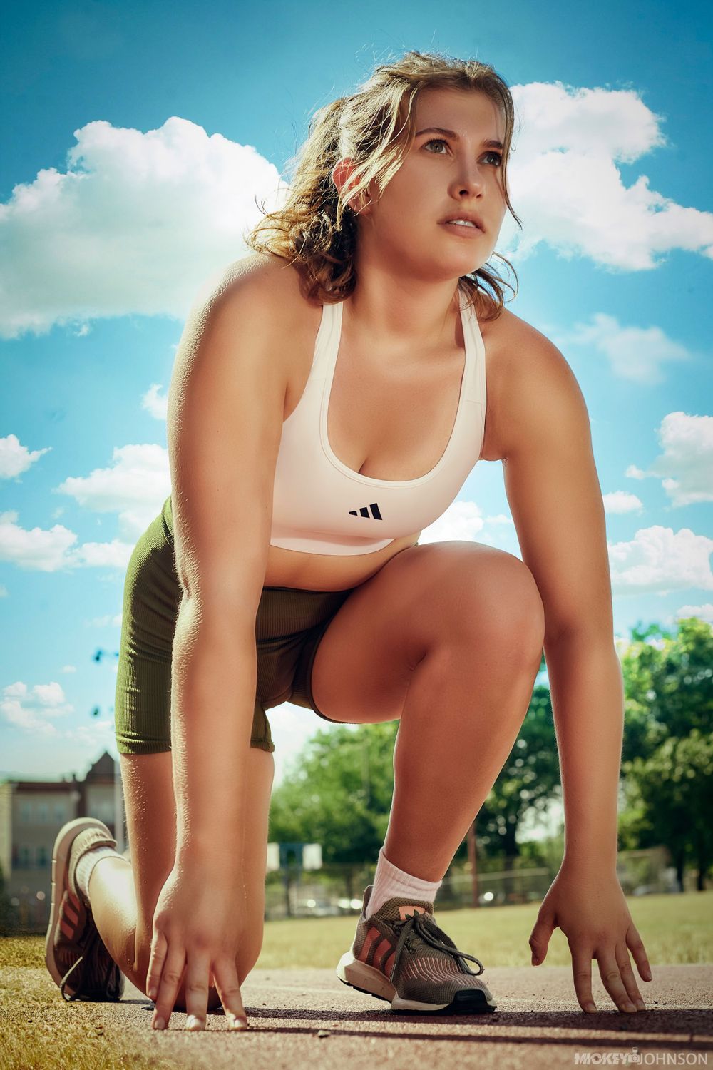 Low angle sports photography of runner in starting position against blue sky.