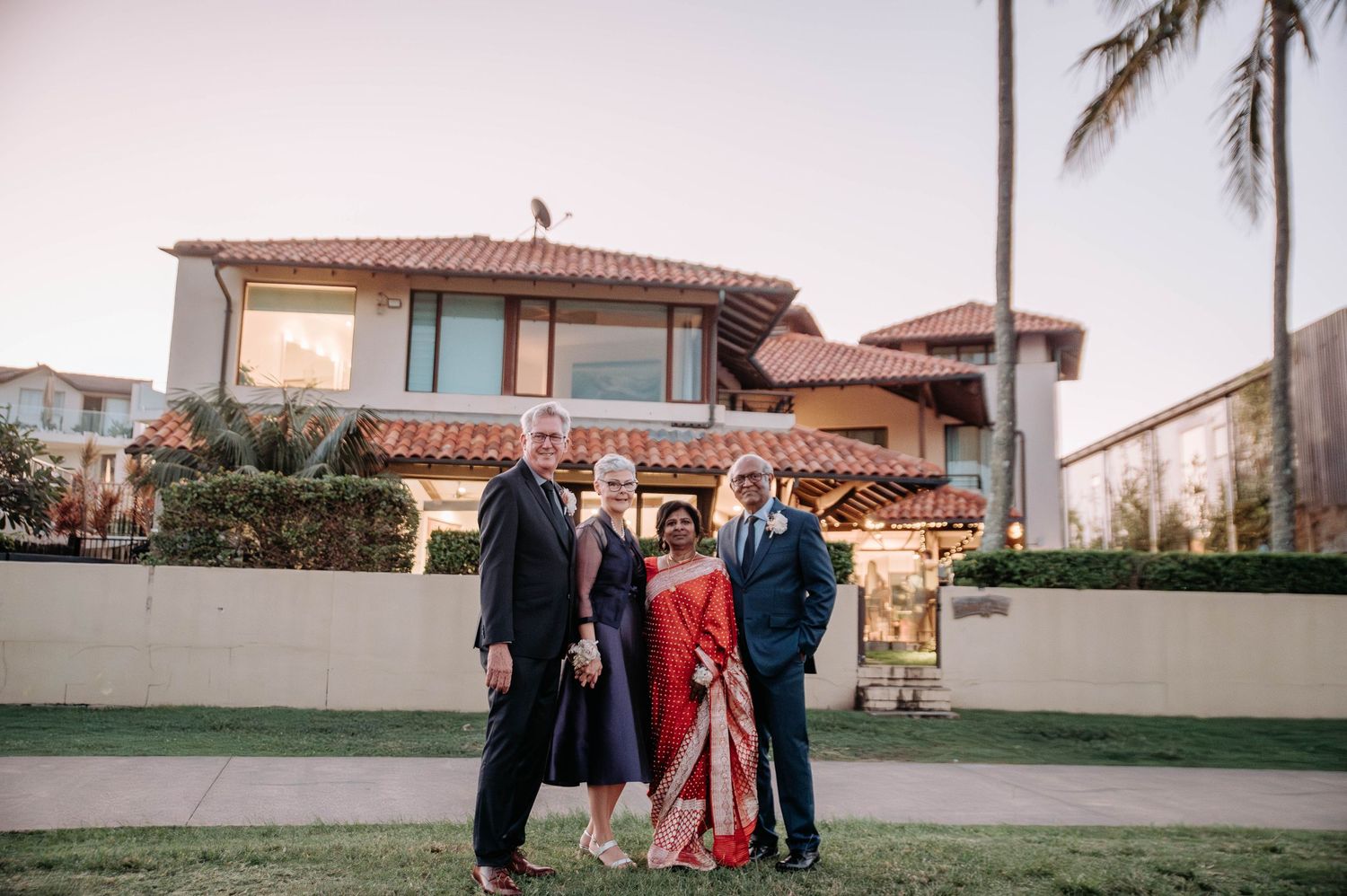 A family poses for a portrait outside a Mediterranean-style house.