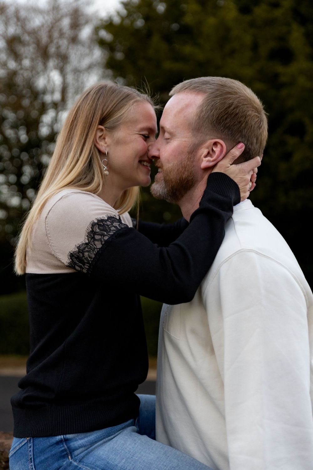 A romantic couple shares intimate moments while wearing contrasting black and white sweaters outdoors.