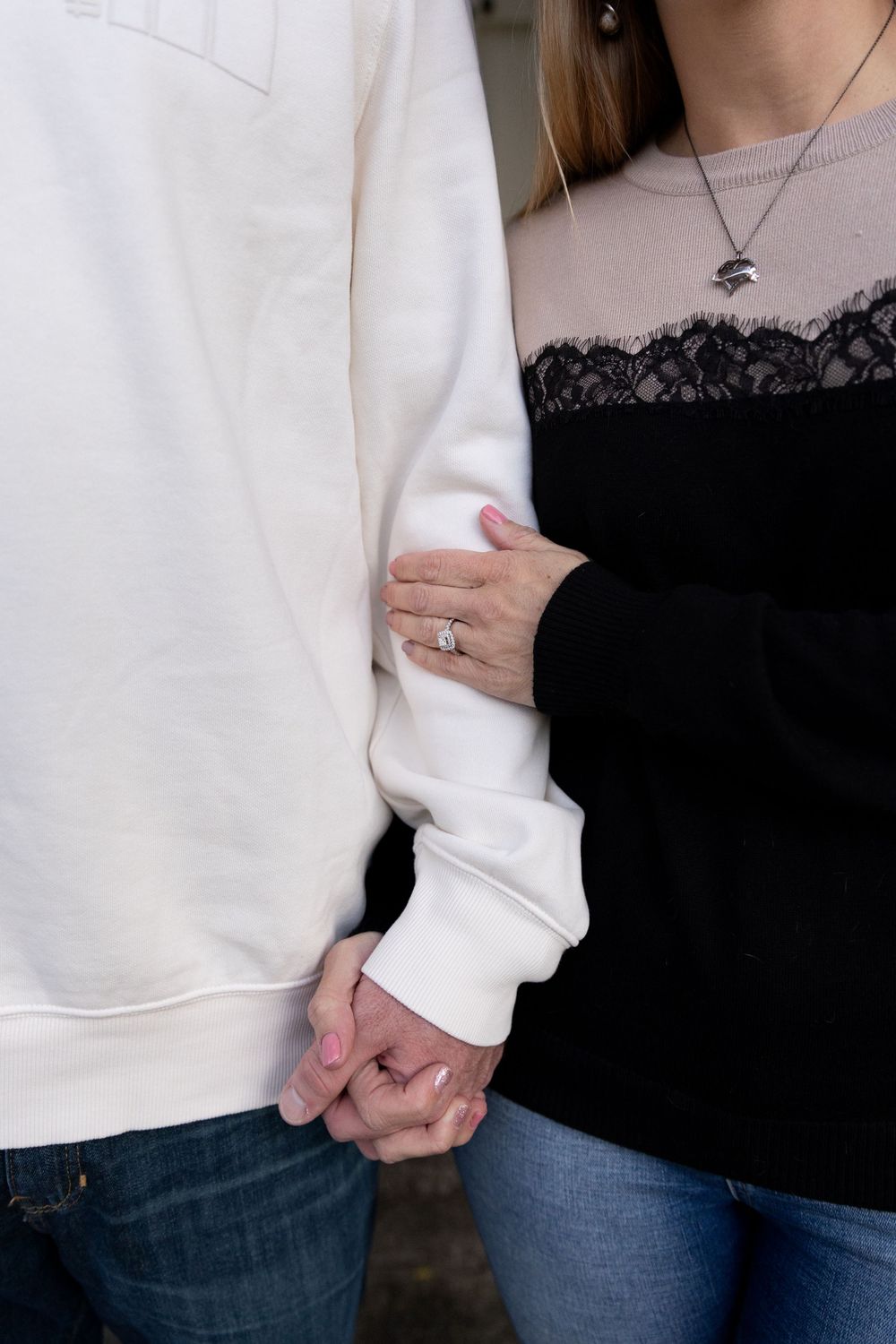 Close-up series showing two people holding hands while wearing casual white sweaters and blue jeans.