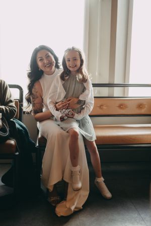 Mother and daughter share a joyful moment together sitting on a wooden bench.