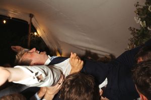 A person crowd surfing at a concert while being held up by the audience in a dimly lit venue.
