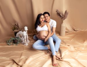 Minimalist studio maternity photo with neutral tones and pampas grass decor.